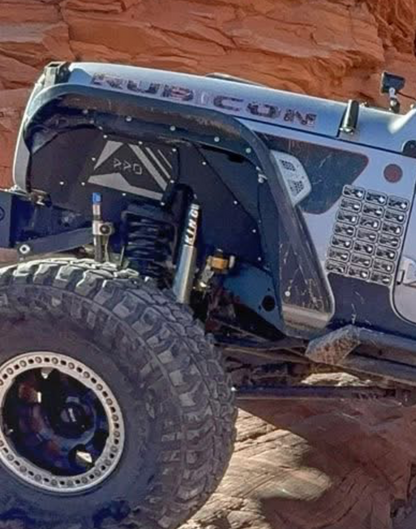 Off-road vehicle climbing a rocky incline with Rock Ready Inner Fenders branding.